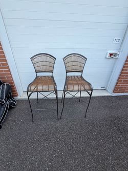 wrought iron counter stool featuring  metal frame paired and woven faux bamboo and rattan seat and backrest. Imperfections. Used in good condition the