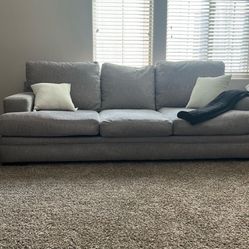 Gray Couch With 2 Throw Pillows and Small Blanket