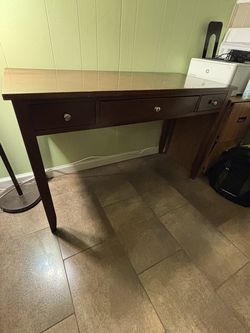 Brown wood desk with pullout, keyboard tray, and two drawers