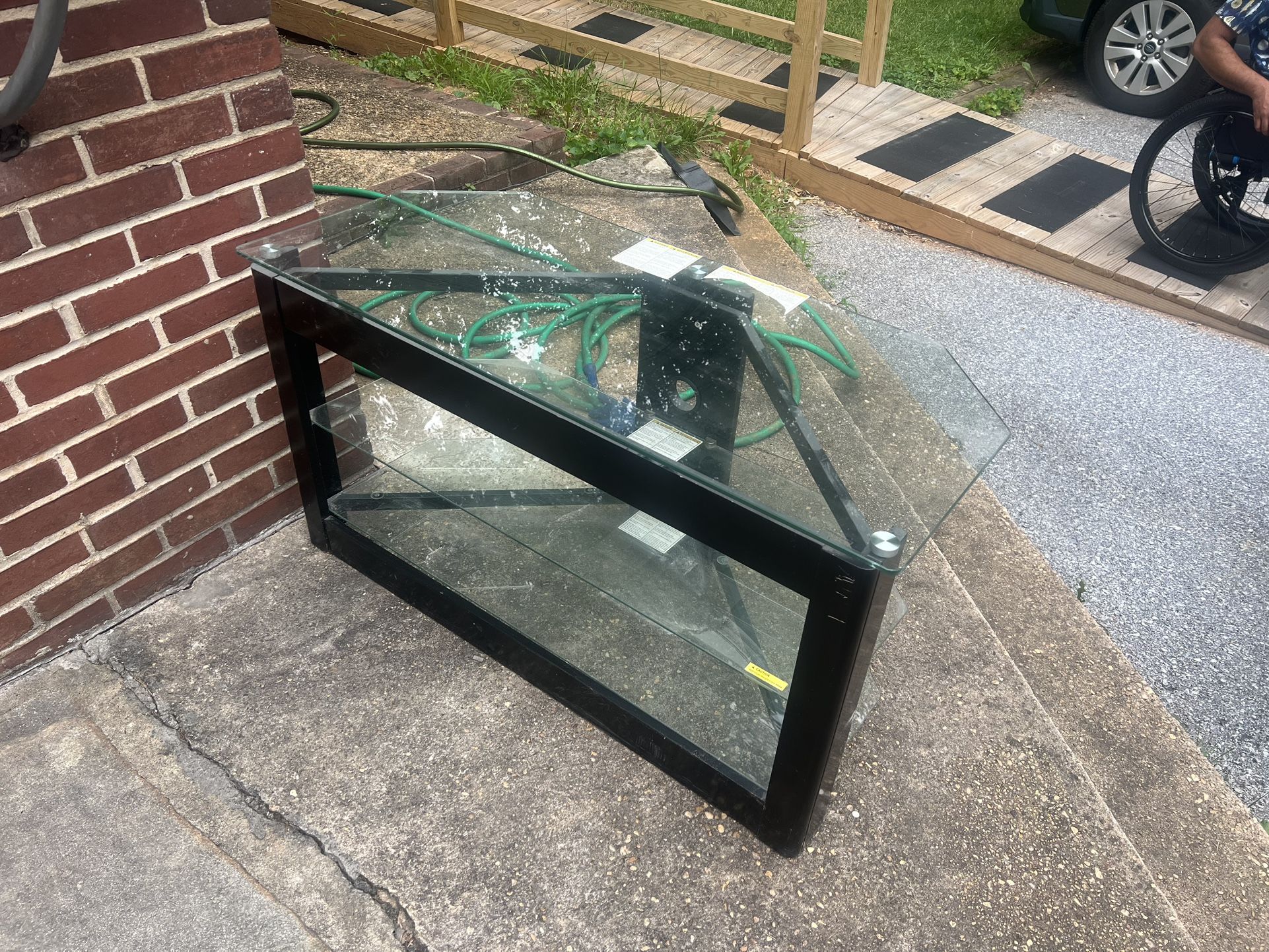 FREE Glass TV Stand Modern glass TV stand with black metal frame. Features: • 3 tempered glass shelves • Cable management holes in the back • Angl