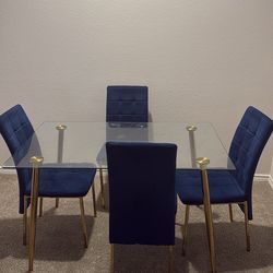 Glass dinning table with 4 gold/ royal blue chairs.