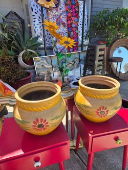 Two yellow terracotta flowerpots with hand-painted floral details in red and green.