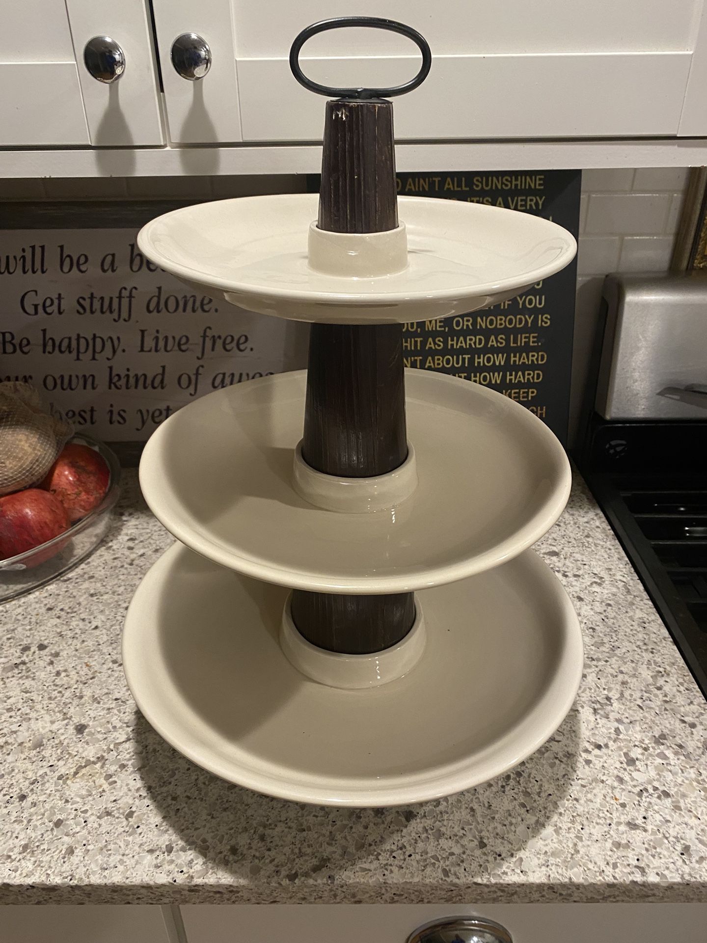 three-tiered serving tray with cream-colored plates* and dark brown wooden center columns…. bottom…* see second photo the bottom tier had a crack that