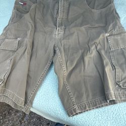 vintage Tommy Hilfiger cargo shorts, likely from the 1990s, featuring a baggy carpenter style, multiple pockets, and the brand's flag logo on the back