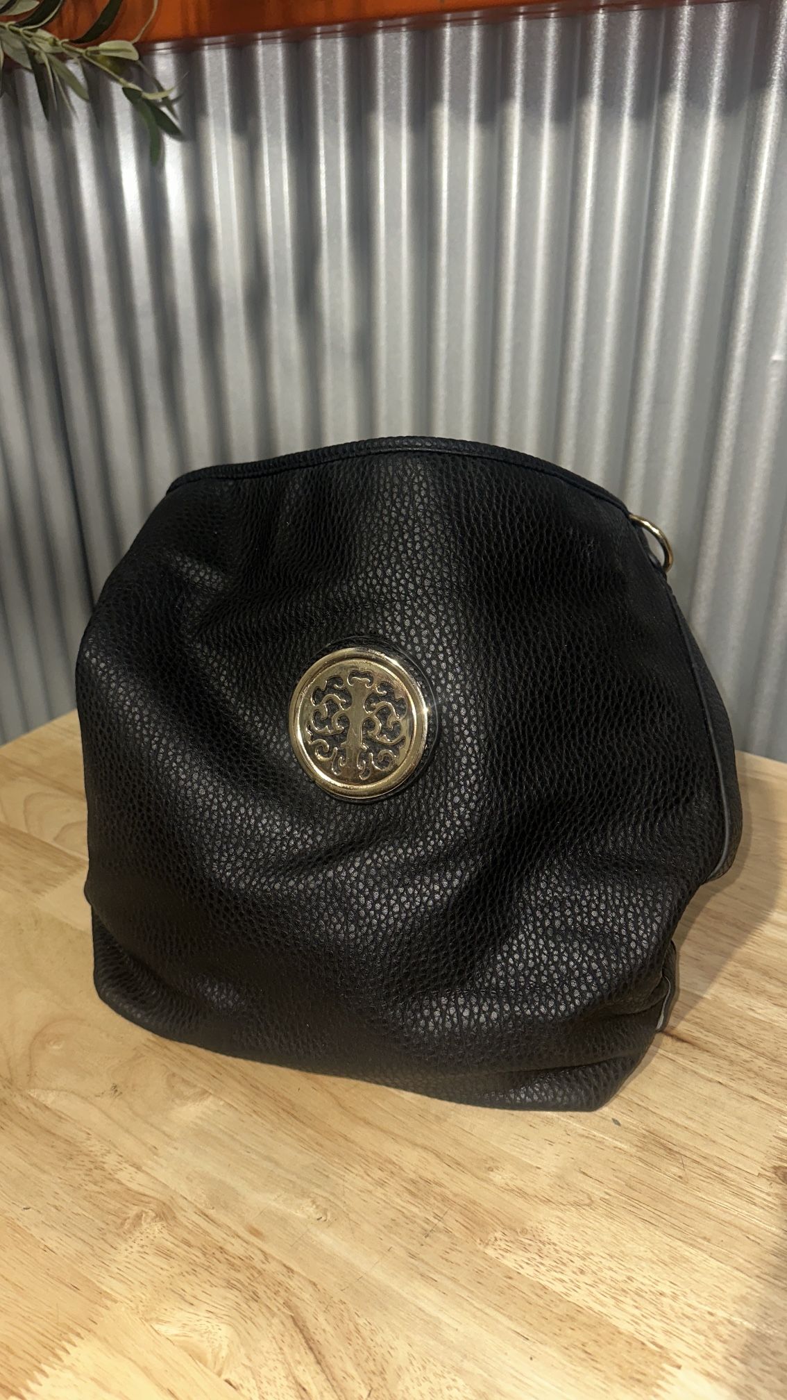 black leather carry-all bag with gold medallion