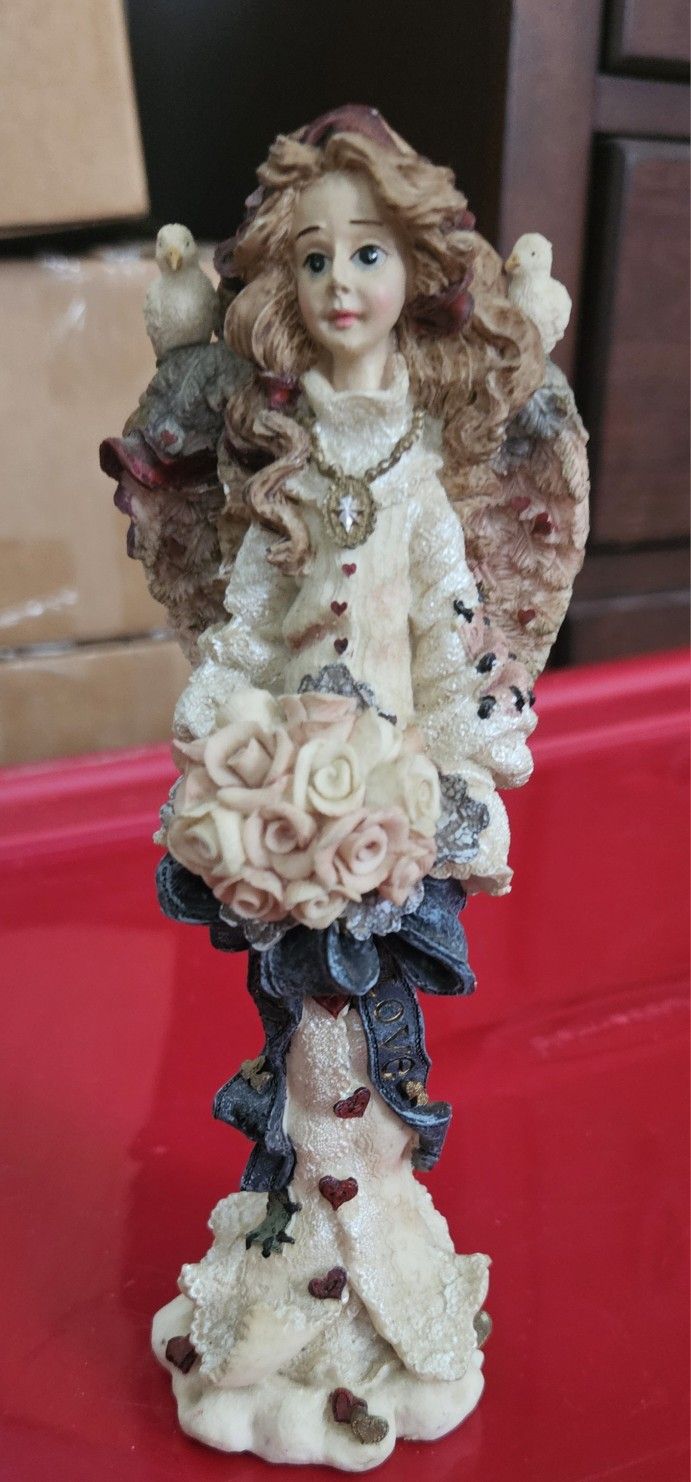 angel figurine holding rose bouquet
