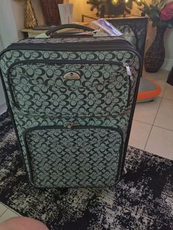 American Flyer rolling softside suitcase featuring a black and gray repeating monogram pattern