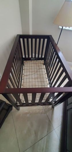 Dark brown wooden crib with mattress