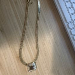 Christian Dior necklace features a gold-tone chain and a pendant with a central purple stone surrounded by clear crystals