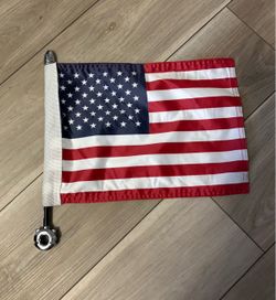 small United States flag (the Stars and Stripes) mounted on a short pole with a chrome tip and a clamp-style base at the bottom.
