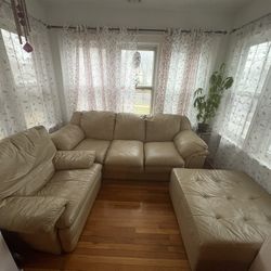 The set features a beige leather couch, a Center Cushion and matching reclining chair. 