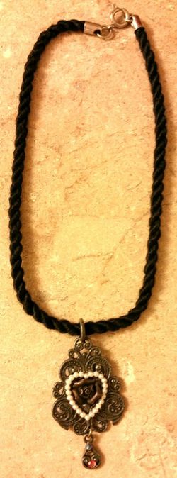 Choker necklace it is vintage and rustic look to it. It is handmade from soft rope and has a decorative heart with flowers and pearls around it.
