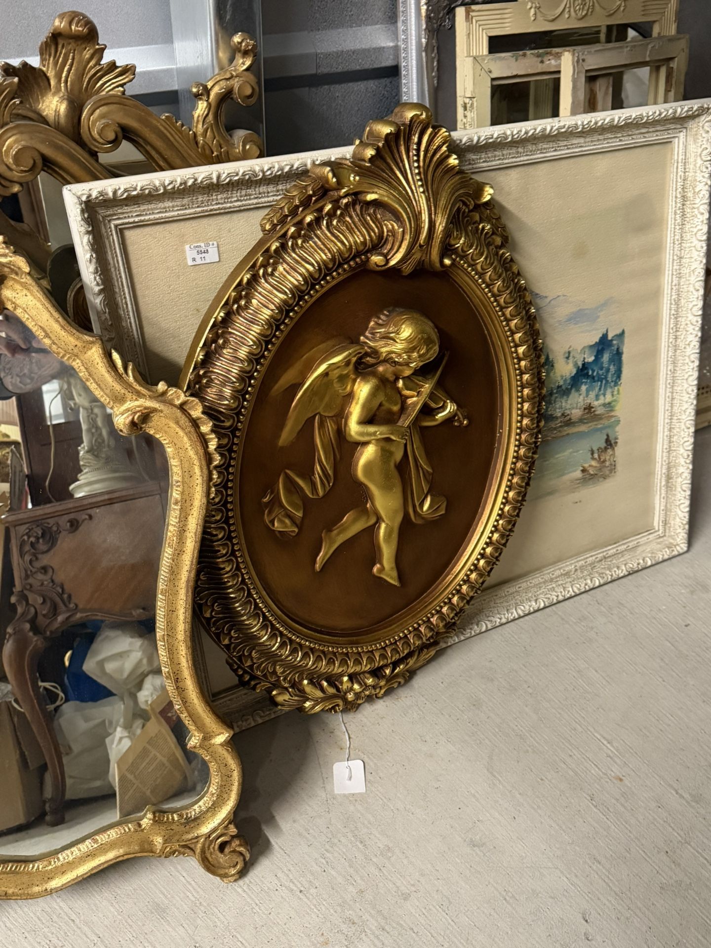 Gilded relief cherub playing violin wall plaque in ornate frame.