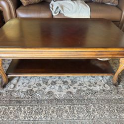 dark brown wood coffee table with a lower shelf and carved legs