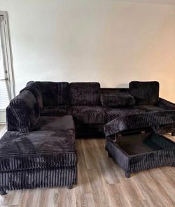 Black Corduroy Fabric Reversible Sectional with Cup Holder and Storage Ottoman. Brand New .