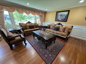 A traditional living room set with matching carved wood , patterned upholstery, 3  coffee table set