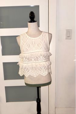 White lace crop top with ruffles from Zara. This openwork blouse features a sleeveless design, round neck, and tiered layers.