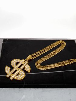 Gold tone dollar sign pendant necklace with rhinestone accents