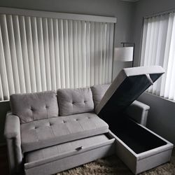 Lilola Home Lucca reversible sleeper sectional sofa with storage chaise in a light gray or beige woven fabric. 