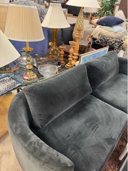 charcoal grey velvet loveseat with rounded arms and a curved back.