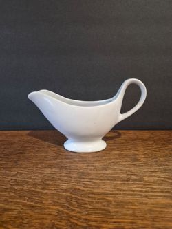White Ceramic Gravy and Sauce Boat with a Footed Pedestal Base, curved pour spout, and looped handle.