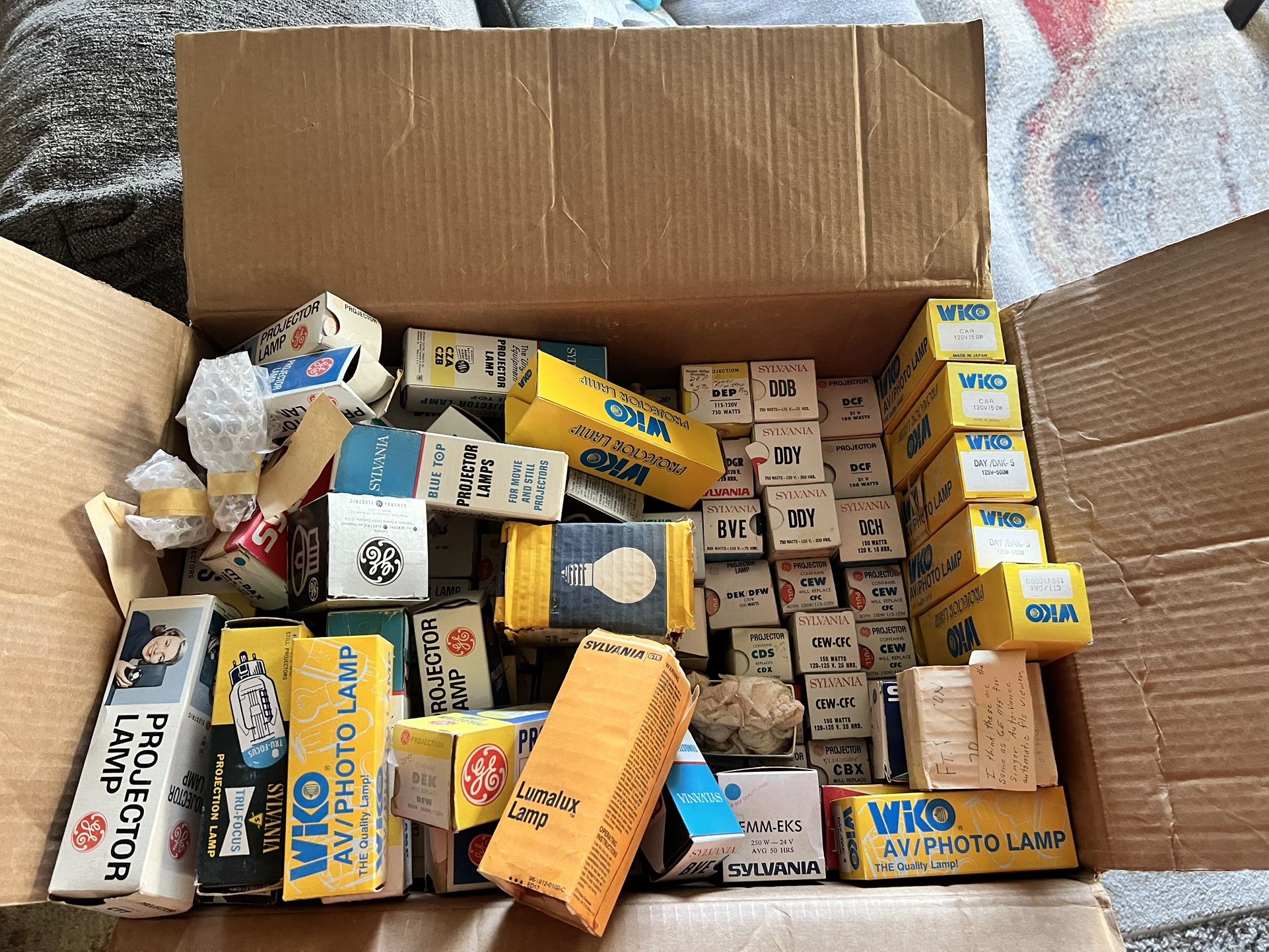 collection of vintage projector lamps and their original packaging. These are replacement lamps used in older movie and still projectors