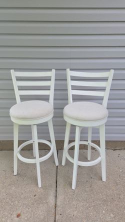 White swivel laddernack bar stools w/ Cream and beige color padded seats.