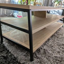 Three-Tier TV Stand In Vintage Oak Coloration With A Black Metal Frame.