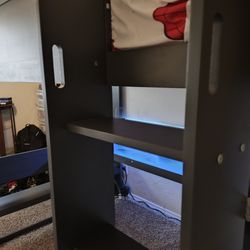 A bunk bed with a desk under the bed 
