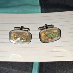 These vintage cufflink accessories feature iridescent abalone shell inlays set within a silver-toned rectangular fram