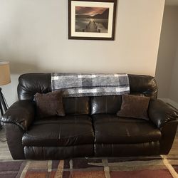 Brown Leather Couch W/ Pillows And Rug.