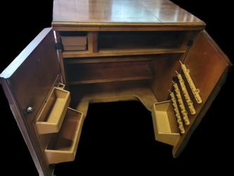 vintage 1970s rolling wooden sewing machine cabinet, featuring a fold-out top surface, two faux-top drawers, and cabinet doors with ornate geometric p