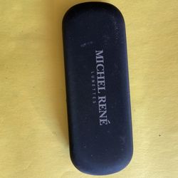 Eyeglasses case • The outer shell is black and made of a hard material with a fine texture. • The inner lining is a light gray or white flocking/soft 