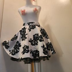 This product is a vintage style 1950's circle skirt by the brand City Triangles in a poodle style design of black and white floral Sz L/13
