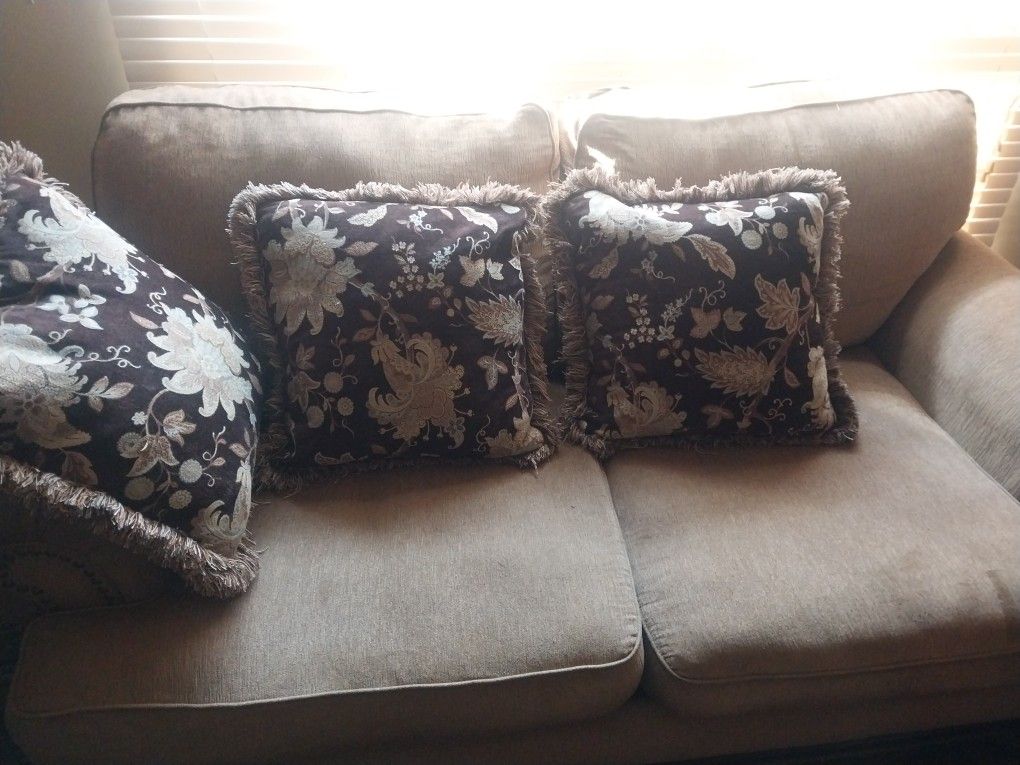 A Sofa and comfortable chair with center table with pillows