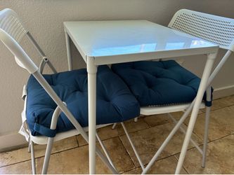 Small table with 2 chairs and 2 blue pillows