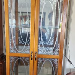 light wood curio cabinet featuring two doors with etched floral glass patterns and a mirrored back for displaying collectible