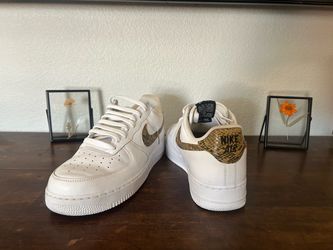 Classic leather Nike Air Force 1 '07 sneakers with snakeskin-patterned swoosh and heel tab. These white low-top shoes have a perforated toe box and ru