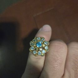 vintage gold-toned ring with a blue rhinestone center stone surrounded by clear rhinestones. 