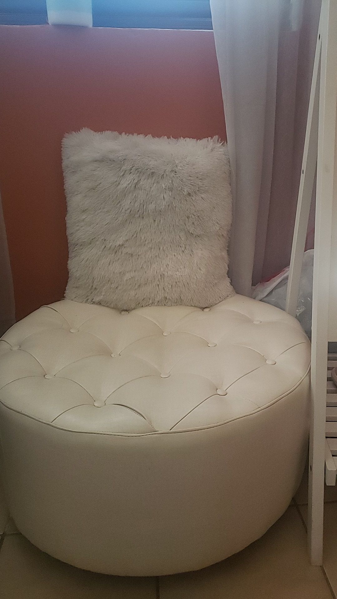 White fluffy accent pillow and faux leather ottoman