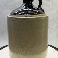 Antique/Vintage American stoneware jug, from the late 19th to early 20th century, featuring a classic two-tone design with a dark brown Albany slip gl