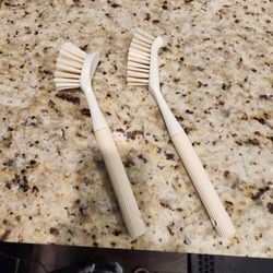 2 kitchen dish scrub brushes with beige ribbed handles, light-colored bristles, and a built-in scraper edge, good condition