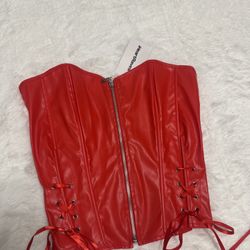 Bold red faux leather corset top with front zip closure. Lace-up sides add adjustable shaping and a flattering silhouette. Smooth finish for a sleek, 