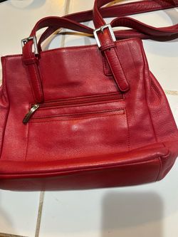 red pebbled leather shoulder bag from Stone & Co. featuring an exterior zippered pocket with a branded zipper pull and buckle strap details on the han