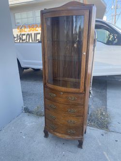 curved-glass curio cabinet with a multi-drawer base 22” Wide X 12” Deep X 70” High