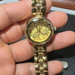 gold-tone Louis Vuitton women's watch featuring a faceted crystal and date displa