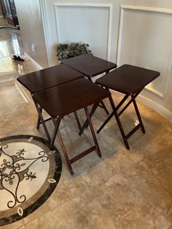 Four dark-wood folding TV tray/snack tables