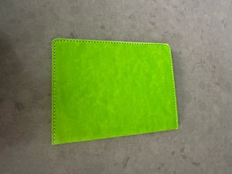 This is a United States passport holder cover. It's a bright green color. It's made of faux leather material.