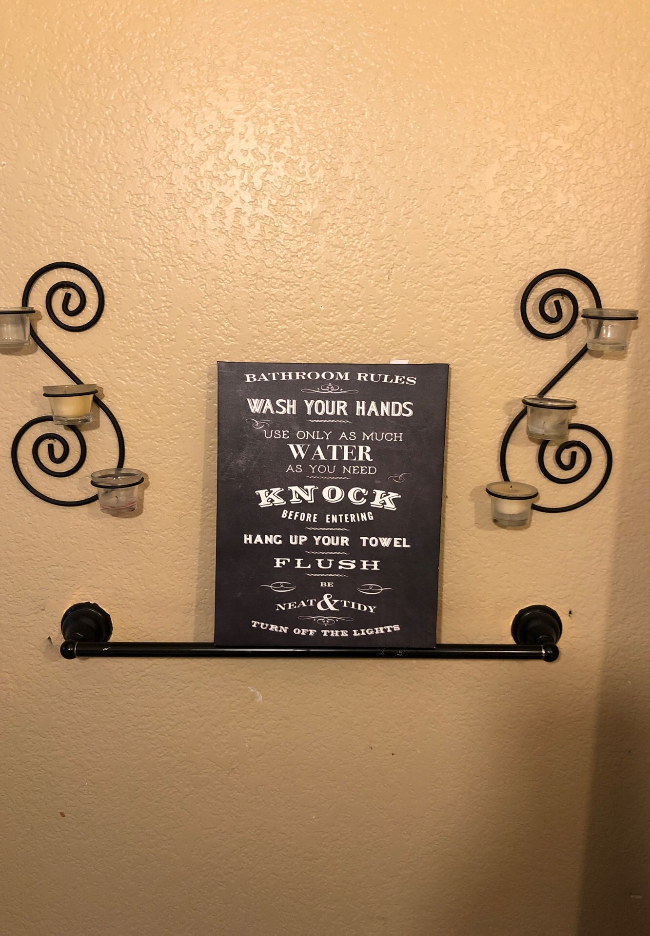 To wall sconces with two candleholders and a bathroom sign.