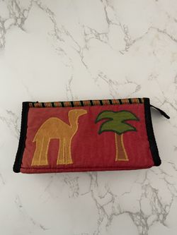 Red fabric pouch with camel and palm tree embroidery.